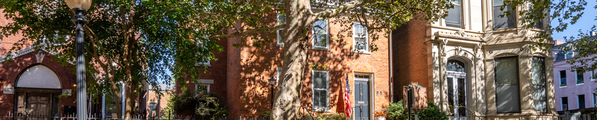 Wide view of the Betts House exterior with brick buildings, trees, and a flag